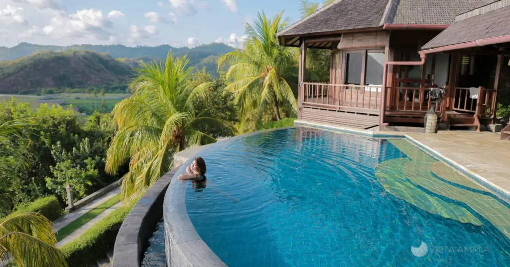 piscina infinita de frente para o mar, usando o celular para planejar a próxima viagem. Dicas para viajar barato em 2025.
